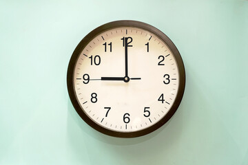 black and white analog clock blue background at nine o'clock