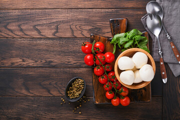 Caprese salad, ingredients for cooking. Cutting wooden board with traditional caprese preparation...