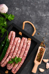 Raw sausages. Bratwurst or sausages with ingredients on cutting board with spices on a stone...