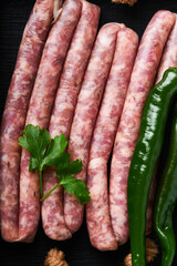 Raw sausages. Bratwurst or sausages with ingredients on cutting board with spices on a stone...