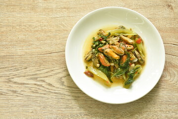 spicy stir fried mussel with slice onion and basil leaf on plate