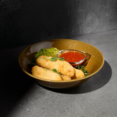Cheese sticks in minimal style on gray stone background. Fried Cheese with spicy sauce on concrete table with hard shadow. Mozzarella sticks on dark  stone background. Minimal menu concept.