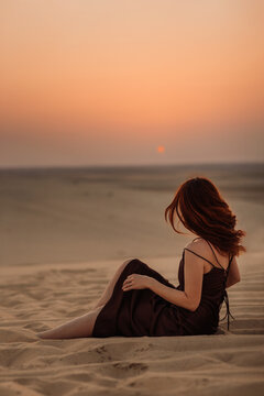 Ginger woman admiring sunset in desert