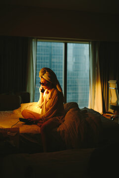 Young lady having phone conversation in hotel room