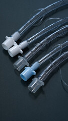 endotracheal tubes of different diameters lie on a dark background.  close-up