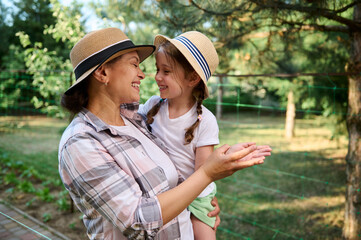 Fototapeta premium Mom and daughter in family eco farm. Instilling love for Earth and farming from childhood. Growing organic vegetables 