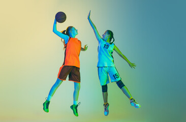Fototapeta na wymiar Attack and defense. Female basketball players, young girls, teen in action with basketball ball isolated on neoned background. Concept of sport, team, enegry, competition, skills