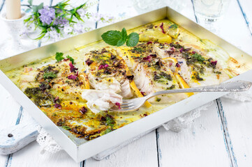 Traditional German pikeperch filet with pesto and lemon slices served as close-up on a metal tray