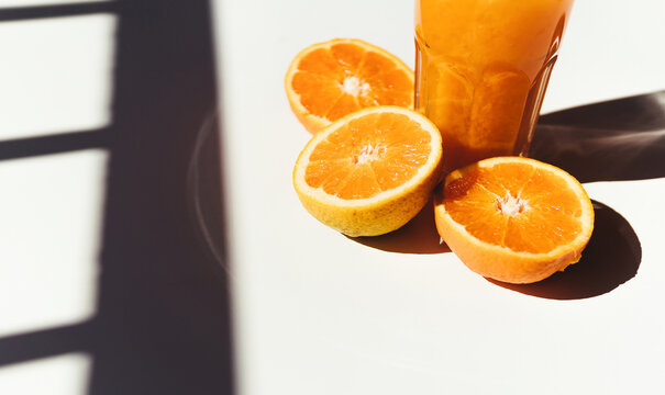 Juice and oranges on sunlit table