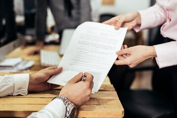 Faceless man signing paper in office