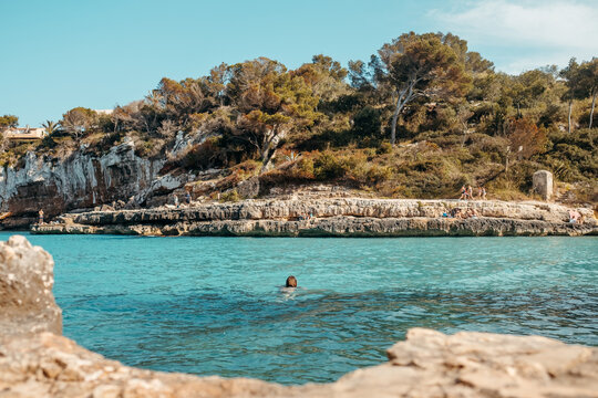 Anonymous lady swimming on rocky coast