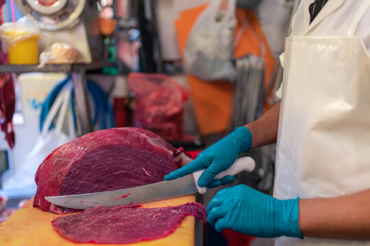 Crop man cutting meat in butchery