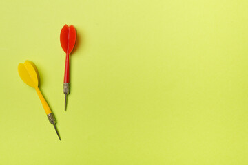 Red and yellow darts on color background, top view