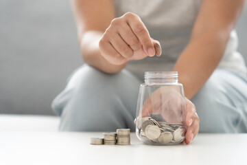 Woman holding a jar full with Thai currency coins. Concept of saving.  Working mother work and save money for family expenses.