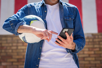 Anonymous man With Ball Using Smart Phone