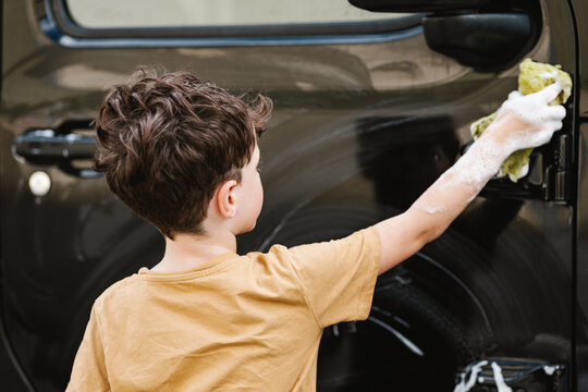 Boy Cleaning Black Car With Sponge And Soap