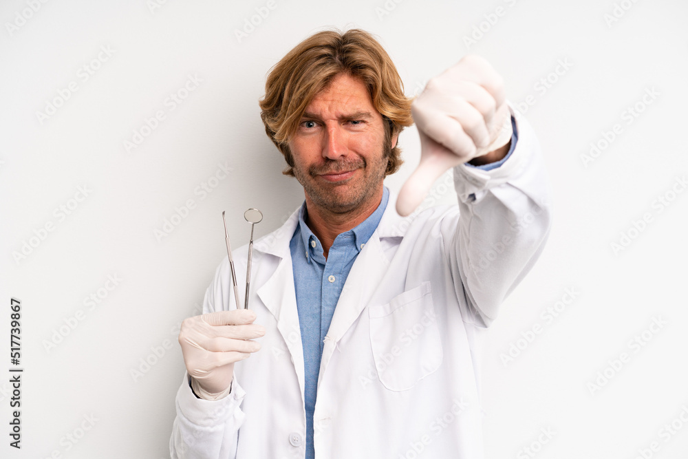 Wall mural blond adult man feeling cross,showing thumbs down. dentist concept