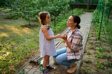 Loving mother and her lovely daughter enjoying gardening together, planting and caring for seedlings in the eco farm 