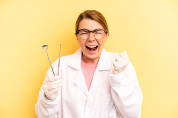 pretty blonde young woman shouting aggressively with an angry expression. dentist student