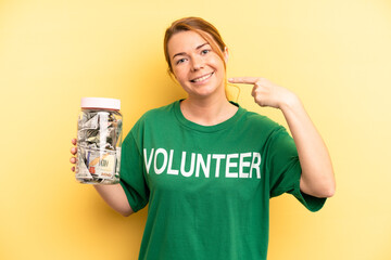 pretty blonde young woman smiling confidently pointing to own broad smile. donation and volunteer...
