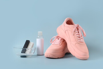 Dirty pink sneakers with brush and special tool for cleaning them on blue background. Concept...
