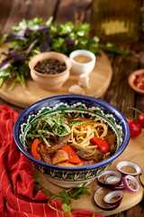 Eastern food - lagman soup with vegetables and noodles on wooden table. Traditional uzbek soup with lamb meat, paprika and noodles in rustic style. Caucasian cuisine on dark wooden background.