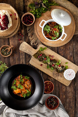 Composition of georgian food: dolma, meat ragout, chicken chakhokhbili on wooden background Traditional georgian dish on dark wooden table. Set of hot appetizers in rustic style.