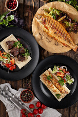 Composition with grilled meat and fish on wooden background. Bbq meat, kebab and rainbow trout in rustic style on dark wooden table. Bbq menu concept for restaurant. Meat and fish on grill.