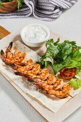 Grilled shrimps with sauce on concrete background. Aesthetic composition with prawn skewer and...