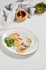 Steamed dumplings shrimp in asian style on white concrete background. Prawn dim sum with sauce on ceramic plate. Shrimp wontons on dish in minimal style. Asian dumplings with seafood.