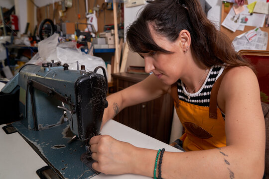 Focused woman using sewing machine in workshop