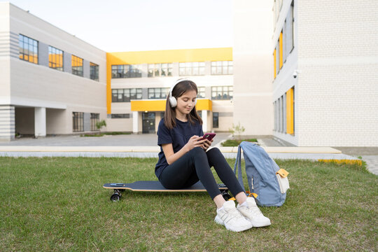Girl browsing smartphone near school
