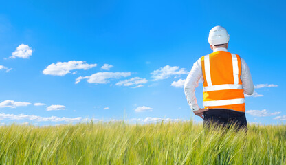 builder in a protective helmet looks at the distance.  man examines the place of the future construction.  engineer-builder in the orange vest.  builder against the backdrop of the blue sky