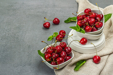 Ripe sweet cherries with fresh mint leaves, traditional summer fruits. Trendy stands, vintage napkin