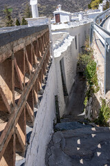 View from the top of stone staircase down on cobblestone street between narrow located ancient traditional stone buildings. One of narrowest cobblestone street in Spain.