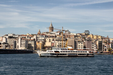 Fototapeta na wymiar View of a traditional ferry boat on Golden Horn part of Bosphorus in Istanbul. Galata tower and Beyoglu district are in the view. It is a sunny summer day.