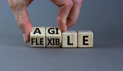 Flexible and agile symbol. Concept words Flexible and agile on wooden cubes. Businessman hand. Beautiful grey table grey background. Business flexible and agile concept. Copy space.