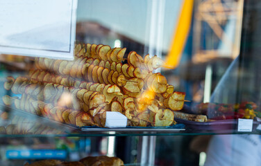 fried potato chips on display behind the glass of a kiosk on the beach