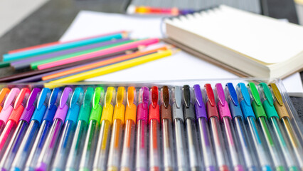 multi-colored gel pens, pencils and notebook lie on the table, concept, selective focus