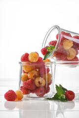 Raw organic yellow and red sunshine raspberries in a glass jar on a white background.