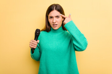 Young caucasian singer woman isolated on yellow background showing a disappointment gesture with forefinger.