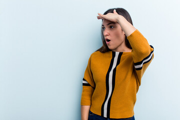 Young caucasian woman isolated on blue background looking far away keeping hand on forehead.