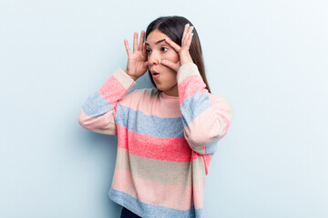 Young caucasian woman isolated on blue background keeping eyes opened to find a success opportunity.