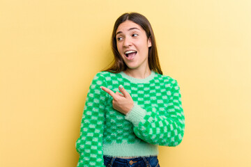 Young caucasian woman isolated on yellow background looks aside smiling, cheerful and pleasant.