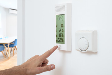 Hand activates burglar alarm control panel on wall in home office workplace interior