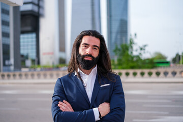 Fototapeta premium Portrait young man with beard and long hair dressed in suit in financial zone
