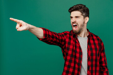 Young sad furious angry man he 20s wearing red shirt grey t-shirt point index finger aside scream shout command do it isolated on plain dark green background studio portrait People lifestyle concept. - obrazy, fototapety, plakaty