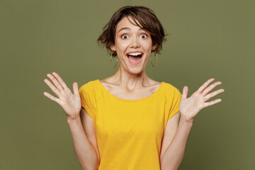 Young excited overjoyed surprised happy woman she 20s wear yellow t-shirt look camera spread hands...