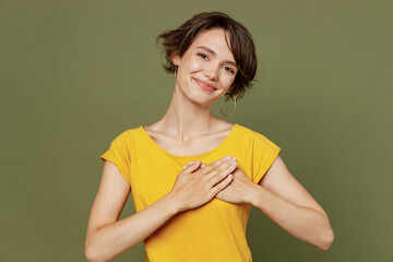 Young smiling cheerful satisfied fun cool happy woman she 20s wear yellow t-shirt put folded hands...