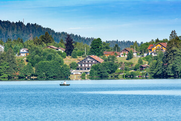 Hotels de montagne et pécheur dans une barque sur les bords du lac de Gérardmer dans les Vosges